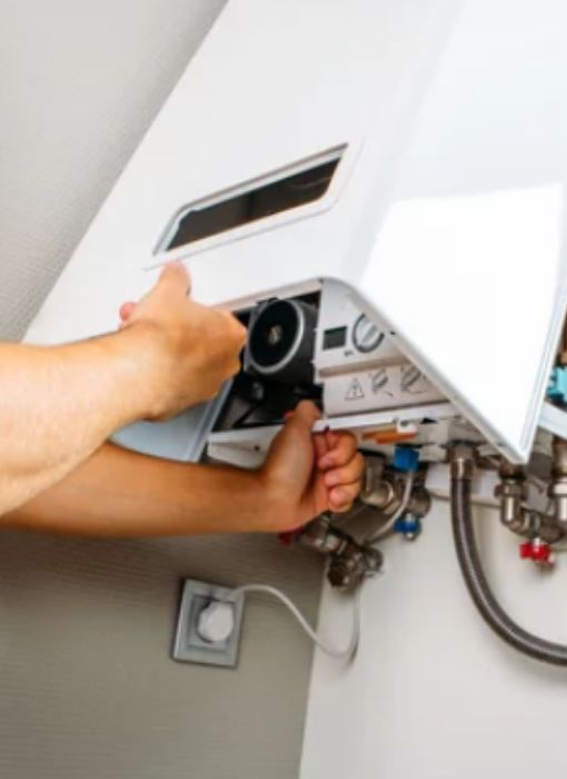 Main réglant le thermostat d’une chaudière gaz murale